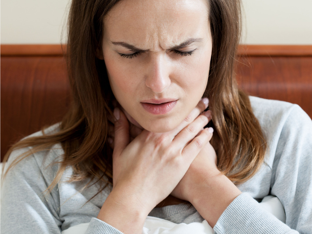 Middle-aged woman grabbing her throat in pain